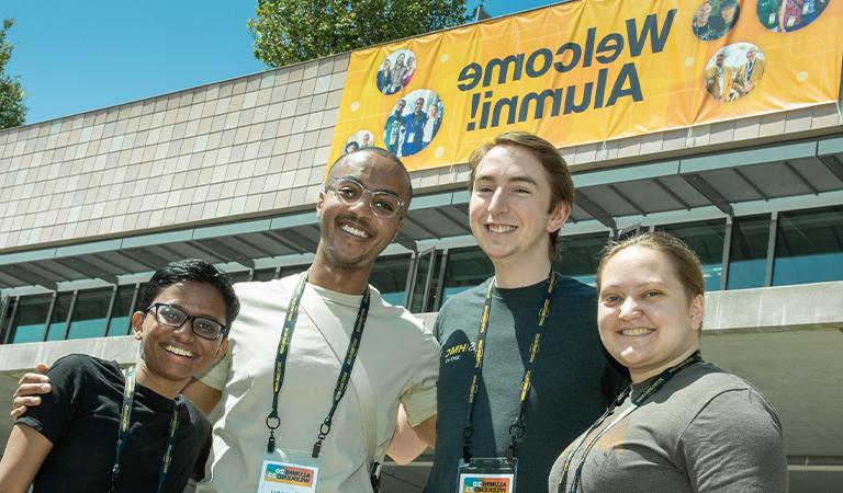 Harvey Mudd alumni pose in front of a banner.